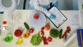 In the shot above, a scientist is sitting in a laboratory. Around her on the table are vegetables and laboratory Royalty Free Stock Photo