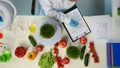 In the shot above, a scientist is sitting in a laboratory. Around her on the table are vegetables and laboratory Royalty Free Stock Photo