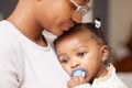 Shes getting tired now. Shot of an adorable baby girl sucking a dummy while being held by her mother at home. Royalty Free Stock Photo