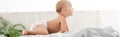 Shot of adorable little child crawling on white sheets in light room