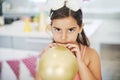 It feels like Im doing all the work. Shot of an adorable little girl blowing up a balloon at her birthday party. Royalty Free Stock Photo