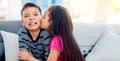 Yuck, girls are weird. Shot of an adorable little girl kissing her big brother on the cheek at home. Royalty Free Stock Photo