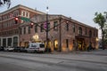 A shot along Bay Street with red brick buildings, cars on the street, people on the sidewalk, traffic signals and lush green trees