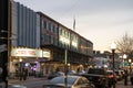 A shot along Broughton Street lined with restaurants, shops, black light posts, bare trees and people standing with cars