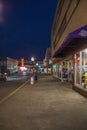 A shot along Broughton Street lined with restaurants, shops, black light posts, bare trees and people standing with cars