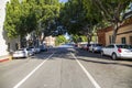 A shot along Green street with parked cars, people walking and tall lush green trees with blue sky in Pasadena California