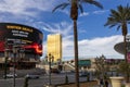 A shot along Las Vegas Blvd with cars driving on the street, hotels and restaurants, people walking, tall lush green palm trees