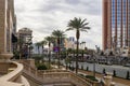 A shot along Las Vegas Blvd with cars driving on the street, The Treasure Island Hotel, people walking, tall lush green palm trees