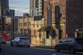 A shot along a street with cars driving, red brick buildings, office buildings and skyscrapers in the city skyline with blue