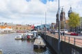 Shot of Amsterdam canal and nearby street. Amsterdam Centraal Station in the background. Variety of transportation means