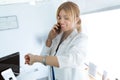 Attractive female doctor talking with her mobile phone while watching her watch in medical consultation Royalty Free Stock Photo