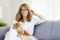 Happy woman sitting on the sofa with her small dog Royalty Free Stock Photo