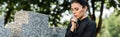 Shot of attractive and sad woman holding rosary beads near tomb Royalty Free Stock Photo