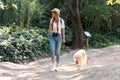 Attractive young amateur photograph woman walking with her dog in the park