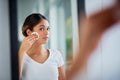 Caring for her vibrantly soft skin. Shot of an attractive young woman cleaning her face with cotton wool in the bathroom Royalty Free Stock Photo