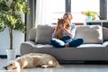 Attractive young woman kissing her little cute dog while sitting in couch with her dogs and cat in living room at home Royalty Free Stock Photo