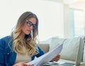 Working over the weekend. Shot of an attractive young woman reading paperwork while working at home. Royalty Free Stock Photo