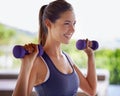 Making magic with her muscles. Shot of an attractive young woman working out with weights. Royalty Free Stock Photo