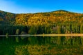 Shot of autumn scenery of Lake Saint Ann in Romania, lush colorful trees reflected in the water Royalty Free Stock Photo