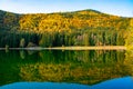 Shot of autumn scenery of Lake Saint Ann in Romania, lush colorful trees reflected in the water Royalty Free Stock Photo