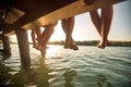 Shot of a barefoot group of friends sitting on the dock on the river. Summer, river, vacation Royalty Free Stock Photo