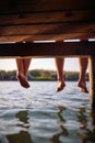 Shot of a barefoot young couple sitting on the dock on the river. Summer, river, vacation