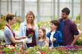 Beautiful family choosing and buying flowers in the greenhouse.