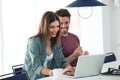 Beautiful lovely young couple using their laptop and having breakfast in the kitchen at home Royalty Free Stock Photo