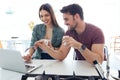 Beautiful lovely young couple using their laptop and having breakfast in the kitchen at home