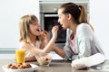 Beautiful mother and daughter feeding cereals to each other at home