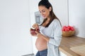 Beautiful pregnant young woman eating strawberries out of bowl in the kitchen at home Royalty Free Stock Photo