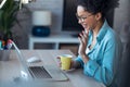 Beautiful young afro business woman making video call with laptop while drinking coffee sitting in the office at home Royalty Free Stock Photo