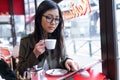 Beautiful young asian woman using her digital tablet while drinking coffee in coffee shop. Royalty Free Stock Photo