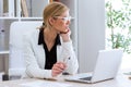 Beautiful young businesswoman looking sideways while working with her laptop in the office. Royalty Free Stock Photo