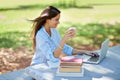 Sunshine study time. Shot of a beautiful young college student sitting with her laptop and books at the park. Royalty Free Stock Photo