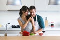 Beautiful young couple having romantic moments, woman feeding her husband with green pepper and smiling in the kitchen. Royalty Free Stock Photo