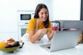 Beautiful young nutritionist woman having an online video call via laptop computer with a friend in the kitchen at home Royalty Free Stock Photo