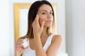 Beautiful young woman caring of her skin standing near mirror in the bathroom Royalty Free Stock Photo