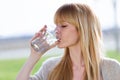 Beautiful young woman drinking water glass in the park.