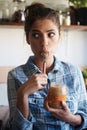 I hope they dont catch me. Shot of a beautiful young woman eating peanut butter out of the jar with a spoon. Royalty Free Stock Photo