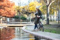 Beautiful young woman sending messages with her smart phone while leaning back on the bike along the river side in a park in. Royalty Free Stock Photo