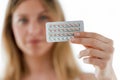 Beautiful young woman showing contraceptive pills over white background.