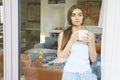 Young woman drinking her morning tea and daydreaming while looking through the window Royalty Free Stock Photo