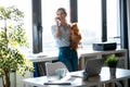 Beautiful young woman talking with mobile phone while holding her little cute dog looking through the window at home Royalty Free Stock Photo