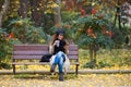 Beautiful young woman using her mobile phone while drinking coffee and sitting in a bench in the street Royalty Free Stock Photo