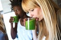 Beautiful young women drinking detox green juice at home.