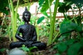 A shot of a buddha statue sitting in a lotus pose surrounded with green plants and trees Royalty Free Stock Photo