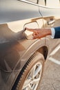 Shot of businessman with his finger on fuel tank of car Royalty Free Stock Photo