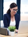 Job satisfaction is a great motivator. Shot of a busy businesswoman working on her laptop in her office.