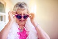 Age is a number, not a limitation. Shot of a carefree elderly woman putting pink glasses on inside of a building. Royalty Free Stock Photo